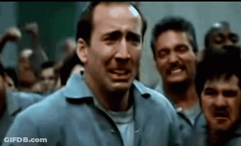 A Man In A Blue Shirt Is Standing In Front Of A Crowd Of Men . GIF
