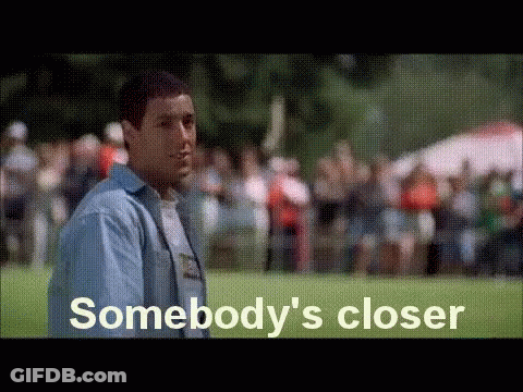 A Man In A Blue Shirt Is Standing In Front Of A Crowd Of People . GIF