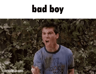 A Man In A Blue Shirt Is Standing In Front Of A Fence And Making A Funny Face . GIF