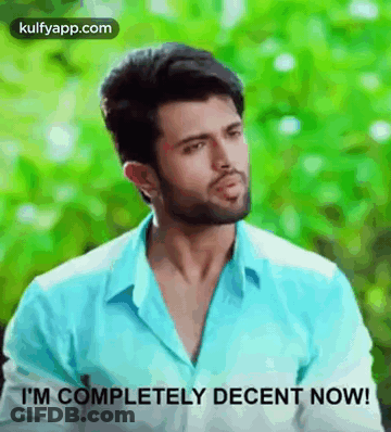 A Man In A Blue Shirt Is Standing In Front Of A Green Background And Says `` I 'M Completely Decent Now ! '' GIF