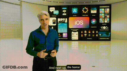 A Man In A Blue Shirt Is Standing In Front Of A Large Screen That Says Ios On It . GIF