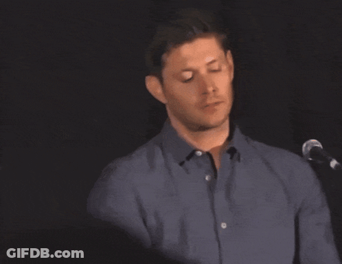 A Man In A Blue Shirt Is Standing In Front Of A Microphone With His Eyes Closed GIF