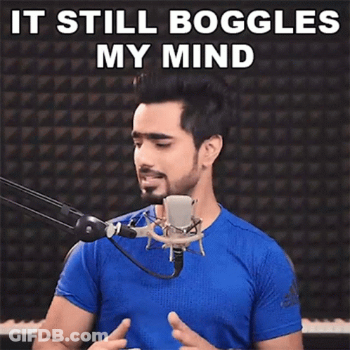 A Man In A Blue Shirt Is Standing In Front Of A Microphone With The Words `` It Still Boggles My Mind '' Above Him . GIF