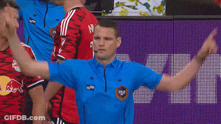 A Man In A Blue Shirt Is Standing In Front Of A Purple Wall . GIF