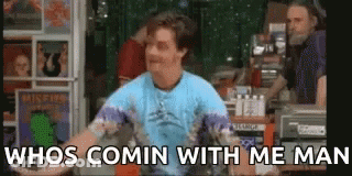 A Man In A Blue Shirt Is Standing In Front Of A Record Store . GIF
