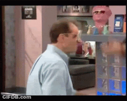 Man In Blue Shirt Standing In Front Of E Sign GIF
