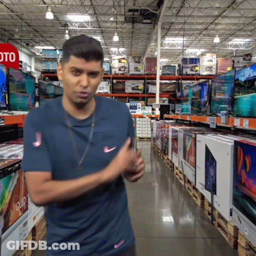A Man In A Blue Shirt Is Standing In Front Of A Sign That Says Oto GIF