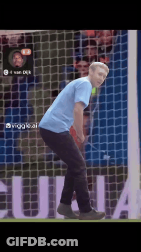 A Man In A Blue Shirt Is Standing In Front Of A Soccer Net With The Number 4 On It GIF