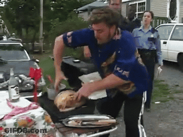 A Man In A Blue Shirt Is Standing In Front Of A Table With A Tray Of Food On It . GIF