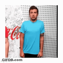 A Man In A Blue Shirt Is Standing In Front Of A Wall With A Coca Cola Logo On It GIF