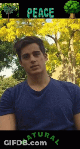 A Man In A Blue Shirt Is Standing In Front Of Trees With The Word Peace Written On It GIF