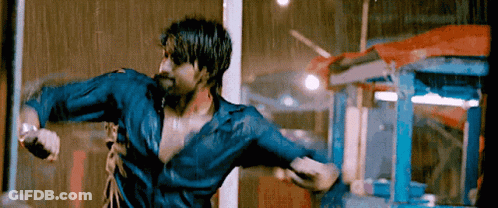 A Man In A Blue Shirt Is Standing In The Rain With His Arms Outstretched GIF