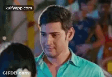 A Man In A Blue Shirt Is Standing Next To A Woman In A Crowded Room . GIF