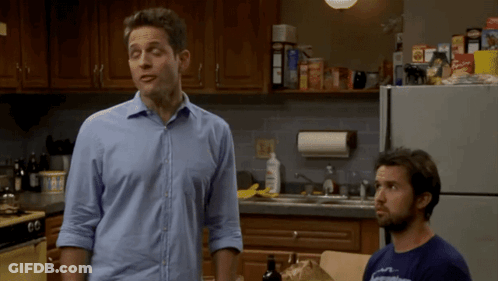 A Man In A Blue Shirt Is Standing Next To Another Man GIF