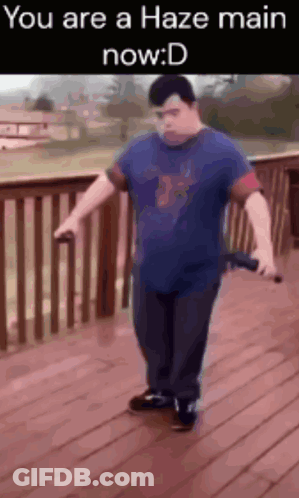 A Man In A Blue Shirt Is Standing On A Wooden Deck Holding A Sword And A Microphone .. GIF