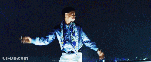 A Man In A Blue Shirt Is Standing With His Arms Outstretched GIF