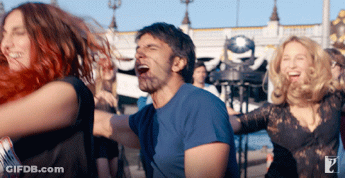 A Man In A Blue Shirt Is Surrounded By Women Dancing GIF