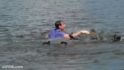 A Man In A Blue Shirt Is Swimming In The Ocean GIF