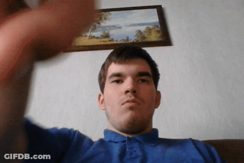 A Man In A Blue Shirt Is Taking A Selfie In Front Of A Framed Picture GIF