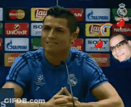 A Man In A Blue Shirt Is Talking Into A Microphone In Front Of A Wall With Advertisements For Lays And Sony GIF