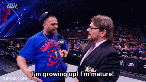 A Man In A Blue Shirt Is Talking Into A Microphone While Another Man Says I 'M Growing Up GIF
