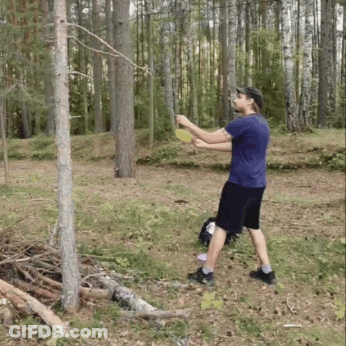 A Man In A Blue Shirt Is Throwing A Frisbee GIF