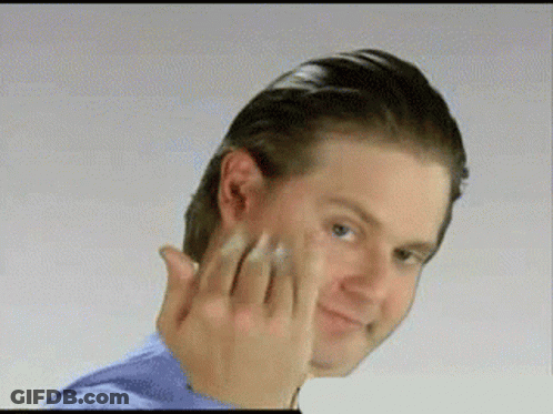 A Man In A Blue Shirt Is Touching His Face GIF