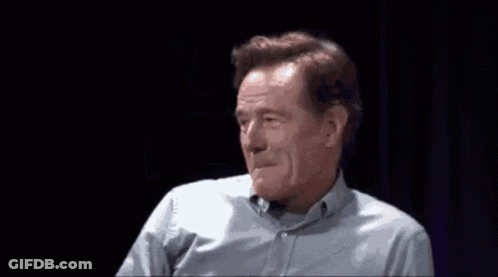 A Man In A Blue Shirt Is Waving His Hand In Front Of His Face GIF