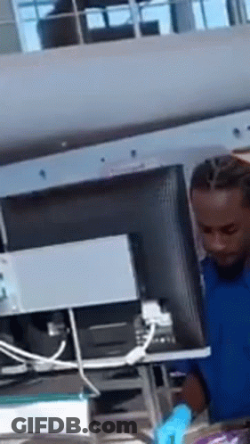 A Man In A Blue Shirt Is Working On A Computer . GIF
