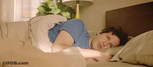 A Man In A Blue Shirt Laying In Bed GIF