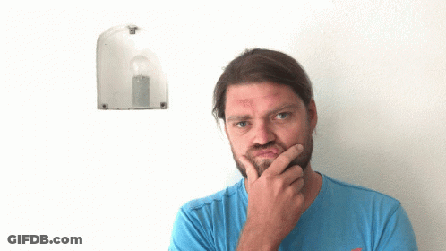 A Man In A Blue Shirt Points Up At A Light Bulb On A Wall GIF