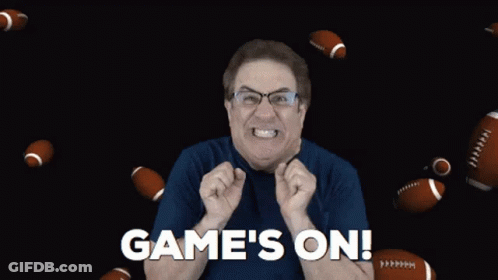 A Man In A Blue Shirt Says Game 'S On With Footballs Flying Around Him GIF