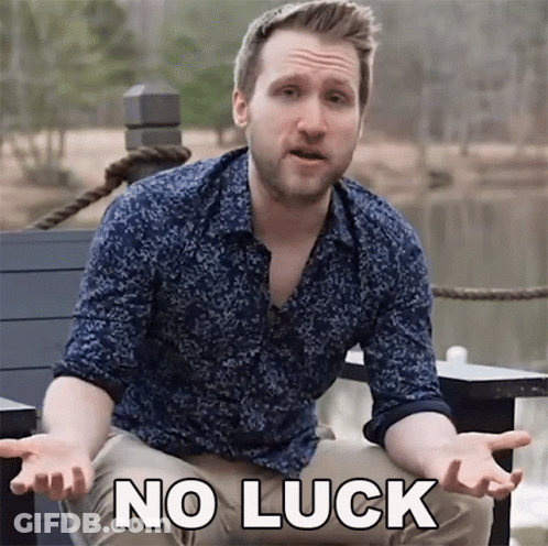 A Man In A Blue Shirt Says No Luck In Front Of A Lake GIF