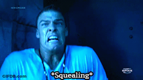 A Man In A Blue Shirt Says Squealing In A Dark Room GIF