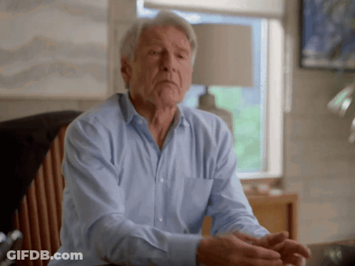 A Man In A Blue Shirt Sits In A Chair GIF