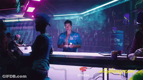A Man In A Blue Shirt Stands At A Bar With Stadia Written On The Wall Behind Him GIF