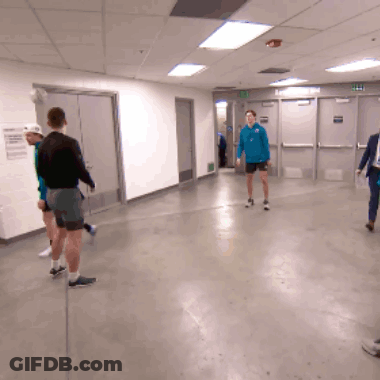 A Man In A Blue Shirt Stands In A Hallway GIF