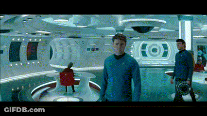 A Man In A Blue Shirt Stands In A Room With A Target On The Wall Behind Him GIF