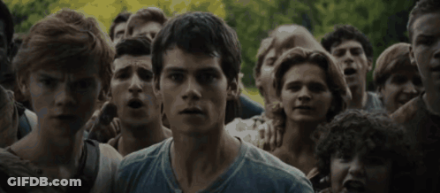 A Man In A Blue Shirt Stands In Front Of A Crowd GIF