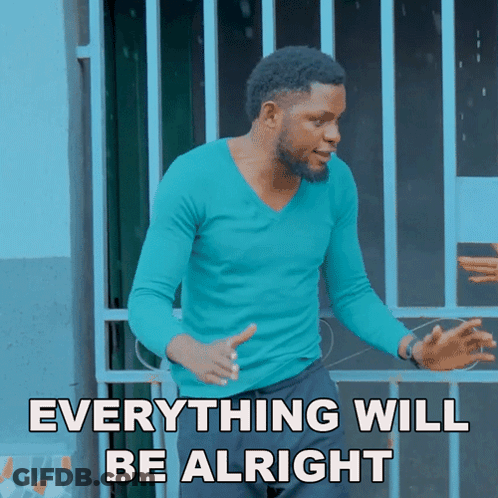 A Man In A Blue Shirt Stands In Front Of A Fence With The Words Everything Will Be Alright GIF