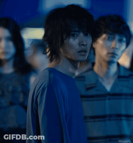 A Man In A Blue Shirt Stands In Front Of A Group Of People GIF