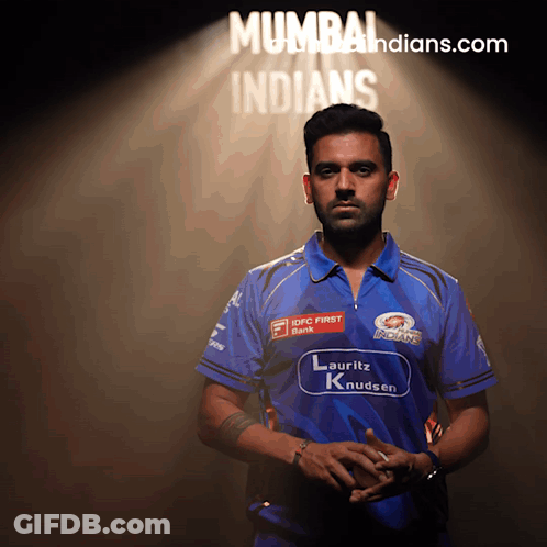 A Man In A Blue Shirt Stands In Front Of A Mumbai Indians Sign GIF