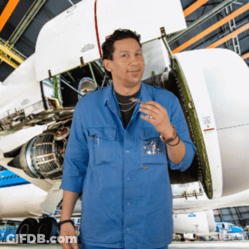 A Man In A Blue Shirt Stands In Front Of A Plane With The Wing Open GIF