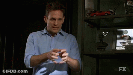 A Man In A Blue Shirt Stands In Front Of A Shelf With Fx Written On It GIF