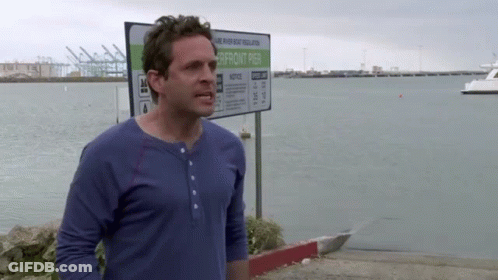 A Man In A Blue Shirt Stands In Front Of A Sign That Says Notice GIF