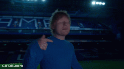 A Man In A Blue Shirt Stands In Front Of A Stadium That Has The Word Jama On It GIF