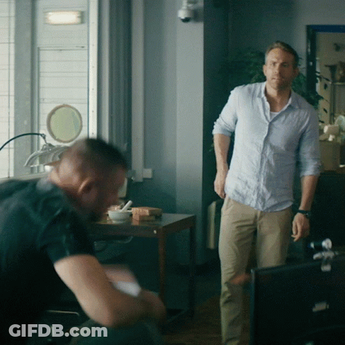A Man In A Blue Shirt Stands Next To Another Man In Khaki Pants GIF