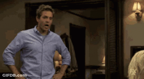 A Man In A Blue Shirt Stands With His Hands On His Hips GIF