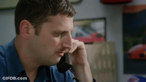 A Man In A Blue Shirt Talking On A Phone GIF