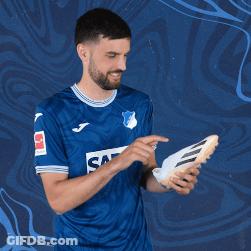 A Man In A Blue Shirt That Says Sap Holds A Soccer Shoe GIF